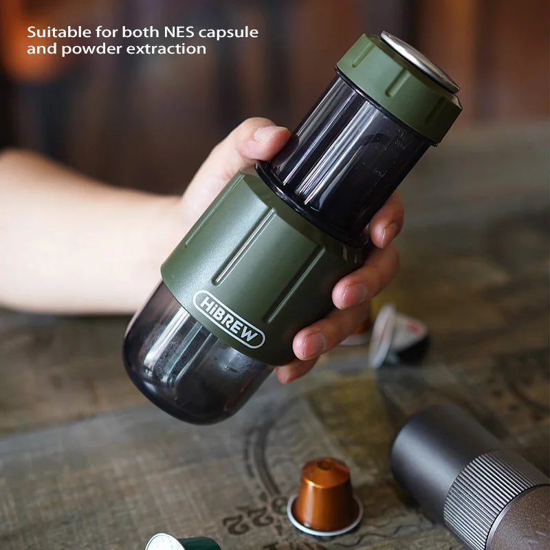 Hand holding the HiBREW espresso maker over a table with coffee capsules — brews capsules or ground coffee