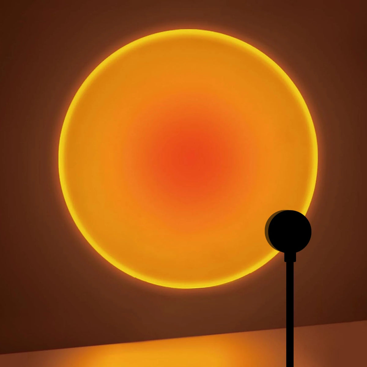 Mini sunset projection lamp silhouetted against the huge amber sunset disc it throws across a wall