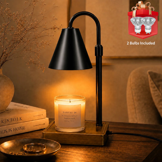 Modern candle warmer lamp in matte black with a brass-tone base, lit over a jar candle on a wooden side table