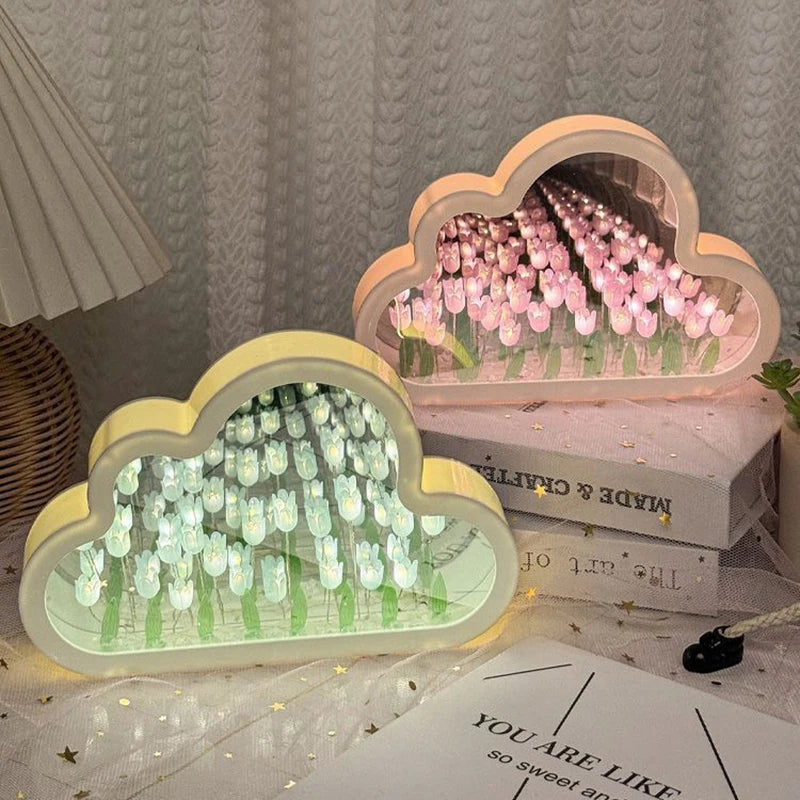 Two cloud tulip mirror lamps glowing on stacked books — white-blue tulips in front, pink behind